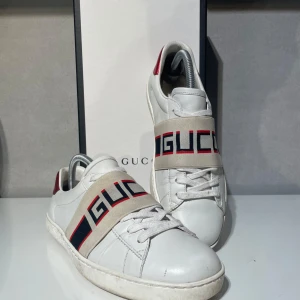 Gucci vita sneakers med logoband - Snygga vita sneakers från Gucci- Kommer med originalkartong,dustbag och kvitto 🧾 🍾🍾och tveka inte att kontakta om du har frågor🍾🥂✅