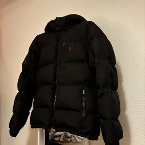 Ralph Lauren pufferjacka - Tja. Säljer nu min vinterjacka som jag köpte ny innan vintern 2024. Den har alltid suttit lite för stort på mig så tänkte unna mig en ny jacka som faktisk passar 😅. Jackan är väldigt sparsamt använd och bra omhändertagen. Skulle säga att den nästan fortfarande ser ut som ny så den får 8/10. Den ska sitta som vanligt så om du har medium så passar den dig. Om du har small vilket jag har så sitter den lite oversized men men.. Köpte även jackan på rea för ca 4000 så där av det bra priset.