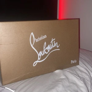 Christian Louboutin marinblå sneakers - Snygga marinblå sneakers från Christian Louboutin med klassisk röd sula och diskret broderad logga på hälen. Skorna har snörning, rund tå och är tillverkade i ett tygmaterial med beige innersida. Perfekta för dig som vill sticka ut med exklusiv stil.
