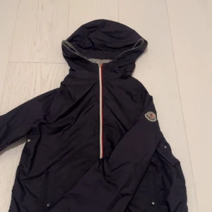 Blå Moncler windbreaker - Tjena! Säljer en mörkblå Moncler windbreaker i storlek 14 år. Denna jackan är i princip ny och är bara andvänd ett fåtal gånger. Inga tecken på andvänding syns. Jackan är självklart äkta! Ett riktigt snyggt plagg! Kom med bud