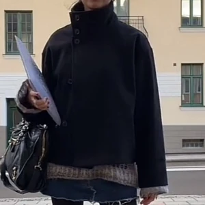 Svart kappa med hög krage - Säljer en svart rock med hög krage och knäppning framtill. Jackan har en rak och loose passform, lång ärm och stilren design. Perfekt för dig som gillar minimalistisk och clean stil. Passar till många olika outfits. Perfekt till höst och vinter❄️🍁