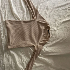 Beige ribbad långärmad tröja Bik Bok - Säljer en beige ribbad långärmad tröja från Bik Bok. Tröjan har rund halsringning och är i ett mjukt, stretchigt material som sitter snyggt på kroppen. Perfekt att styla med jeans eller kjol för en enkel och clean look.