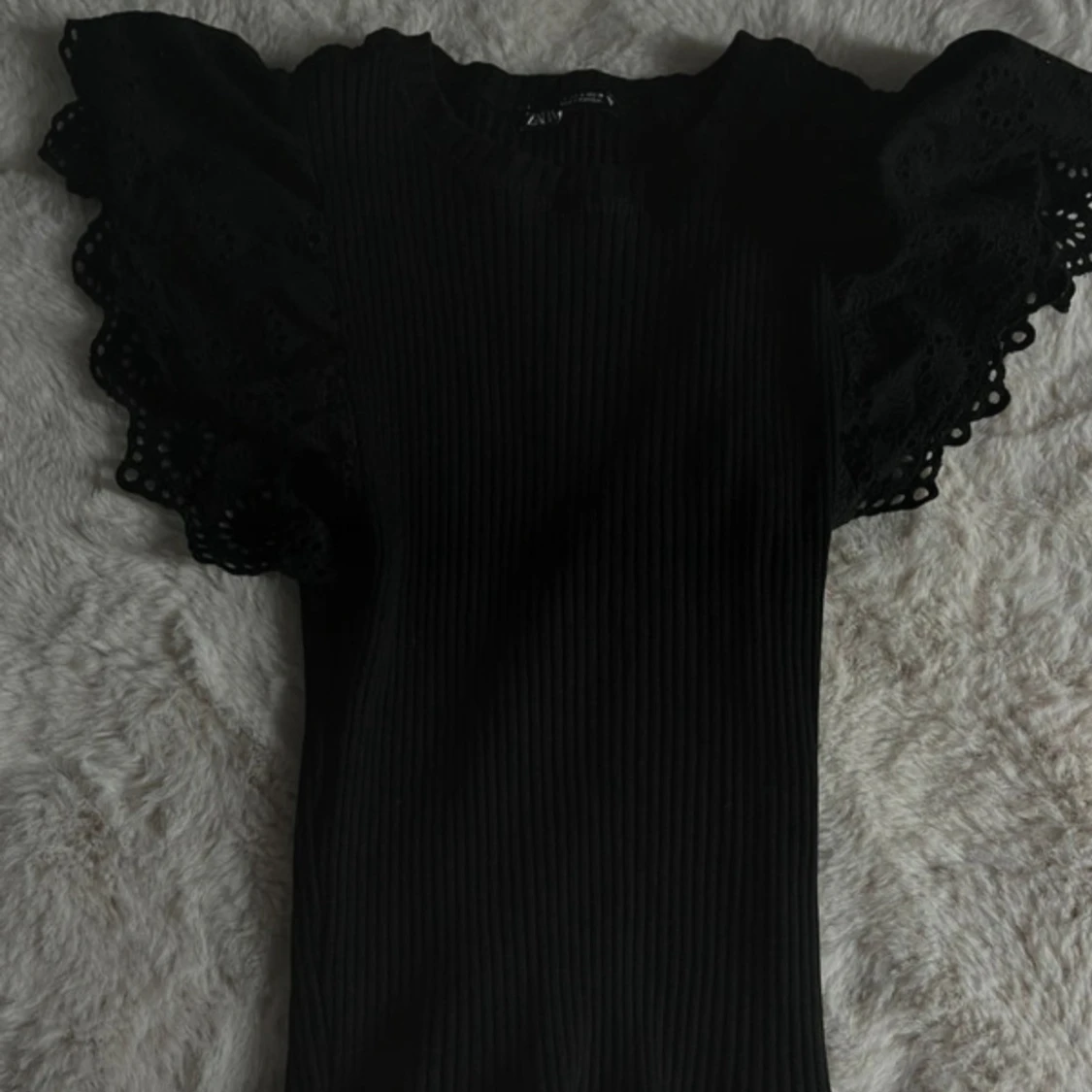 Svart ribbad topp med volangärm