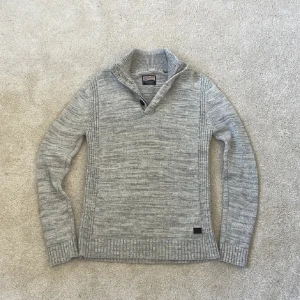 Grå stickad tröja från Petrol Industries | L - Säljer denna snygga grå stickad tröja från Petrol Industries med hög krage och tre svarta knappar framtill. Använd ett par fåtal gånger. Tröjan är perfekt inför lite kyligare dagar!! 