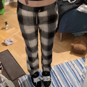 Rutiga byxor med snörning från Kappahl - Snygga rutiga byxor från Kappahl i svart, grått och vitt. De har elastisk midja med snörning och raka ben. Perfekta för dig som gillar en chill och trendig look. Sköna att bära och lätta att matcha med sneakers eller hoodies.