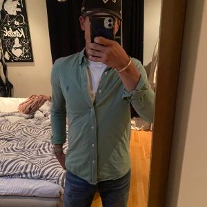 Ralph Lauren skjorta - Snygg grön skjorta från Ralph Lauren feather weight mesh med klassisk krage och knappar hela vägen. Skjortan har lång ärm och den ikoniska blå loggan broderad på bröstet. Perfekt till jeans eller chinos för en clean look. Jättebra skick! Jag är 180cm