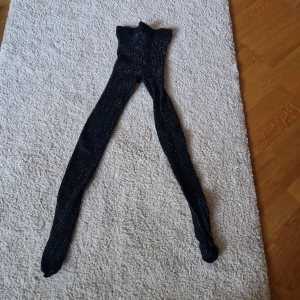 Svarta glittriga strumpbyxor Kappahl - Snygga svarta strumpbyxor från Kappahl i storlek 146/152. De har glittriga inslag och ett ribbat mönster som ger extra stilpoäng. Perfekta när du vill ha lite extra bling på benen och sticka ut med din outfit.