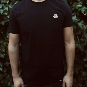 Svart Moncler t-shirt med logga - Svart t-shirt från Moncler med rund hals och korta ärmar. På bröstet sitter Monclers klassiska logotyp i vitt, rött och blått. T-shirten är gjord i mjuk bomull och har en clean, normal passform som funkar till jeans eller.                                                                                                                                                                              Nypris: 2000kr GORILLAPRIZE:1120kr            Skick:10/10 oöppnad         KVITTO MEDKOMMER              