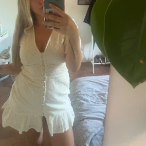 Vit kort klänning med spets och knappar - Supersöt vit kort klänning påminner om adoore. Nypris 700kr