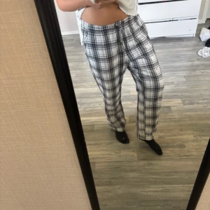 Pyjamas byxor  - Säljer ett par sköna pyjamas byxor med svartvitt rutmönster och dragsko i midjan. Byxorna har en loose fit och är tillverkade i mjukt bomullstyg, perfekta för chill dagar hemma. Klassisk rak modell med bekväm passform.(‼️dom har en fläck som jag visar på bilden)‼️samt välanvända om noppriga hör och där 