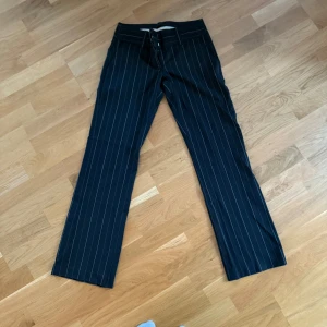 Svarta randiga kostymbyxor Vero Moda - Snygga svarta kostymbyxor från Vero Moda med kritstreck. Byxorna har raka ben och klassisk passform med hällor för bälte. Perfekta för en stilren look och passar till både sneakers och boots. Skulle säga att dom är mer 34 än 36! 