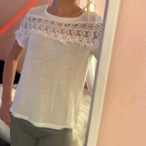 Vit blus med spets från H&M XS - Superfin vit blus från H&M i storlek XS. Toppen har korta ärmar och en snygg spetsdetalj över axlar och bröst, vilket ger en romantisk vibe. Mjuk och lätt i materialet, perfekt till jeans eller kjol. Enkel rund halsringning och rak passform.