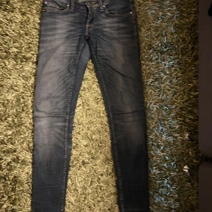 Blå skinny jeans Style Slender 28/32 - Säljer ett par blå jeans i modellen Style Slender, program Julie, med skinny fit och klassisk femficksdesign. Jeansen har snygga slitningar och är i stretchigt denimtyg för en tight passform. Perfekta till sneakers eller boots.