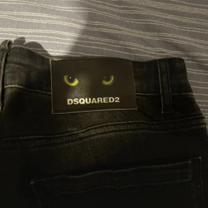 Svarta skinny jeans från Dsquared2 - Snygga svarta jeans från Dsquared2 med coolt slitet och tvättat utseende. Skinny fit med klassiska fem fickor och Dsquared2-logga med ögon på bakfickan. Perfekta för dig som gillar streetstyle och vill sticka ut lite extra.
