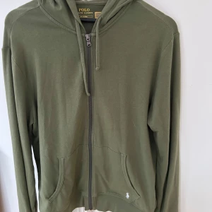 Grön zip hoodie från Polo Ralph Lauren - Hoodie från Polo Ralph Lauren med dragkedja. Lite tunnare material vilket är riktigt skönt. Samt loggan nedtill istället för brösten, väldigt diskret och snyggt! Köpt på NK i Stockholm 