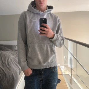 Grå hoodie från Nike med huva - Grå hoodie från Nike! Perfekt till kalla sommarkvällar eller ett gympass. En fläck på framsidan, skulle tro att den går bort i tvätten.  Passar 180+ 75kg💯💶 storlek L men passar M
