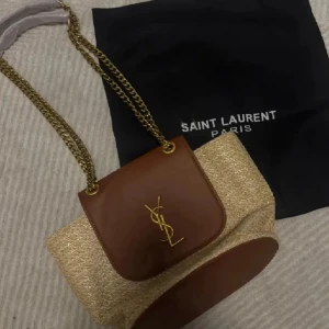 YSL Väska - Säljer en jätte fin YSL väska med tillkommande dustbag. Väskan är helt ny och 100% oanvänd. Måtten är 29x19 cm. Jätte rymlig på insidan och loggan inristad på detaljerna. Tillkommer även ett verifikat kort.🌴❤️☀️.