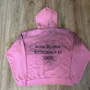 Rosa hoodie Acne Studios Stockholm - Säljer en rosa hoodie från Acne Studios med coolt svart tryck på ryggen: 'Acne Studios STOCKHOLM 1996'. Tröjan har en huva och är i mjuk bomull. Färgen är rosa med mörkare partier som ger en unik vibe. Perfekt för dig som gillar streetwear och vill sticka ut. Tröjan är i storlek s/m. Priset går att diskuteras vid snabb affär