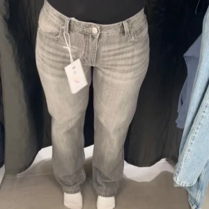 Grå raka jeans i straight fit - Säljer ett par grå jeans med rak passform och klassisk femficksdesign. Jeansen har en snygg tvättad look och normalhög midja. Säljer då den inte kommer till användning 