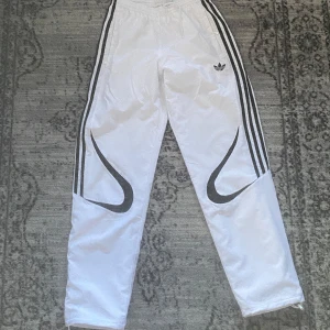 Vita Adidas pants - Snabb leverans! I fantastisk skick använd väldigt få gånger! Säljer ett par vita Adidas trackpants med svarta ränder längs sidorna och stora svarta grafiska detaljer på benen. Byxorna har elastisk midja, meshfoder och klassisk Adidas-logga framtill. Perfekta för en sportig och trendig look.