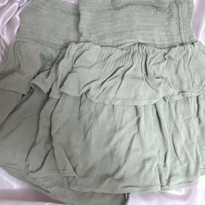 Ljusgrön volangkjol i bomull - Supersöt ljusgrön kjol med volanger och smock i midjan. Kjolen är kort och har en luftig känsla tack vare det tunna bomullstyget. Perfekt för dig som gillar en romantisk och avslappnad stil. Köpte den i Portugal förra året och har inte använt den 