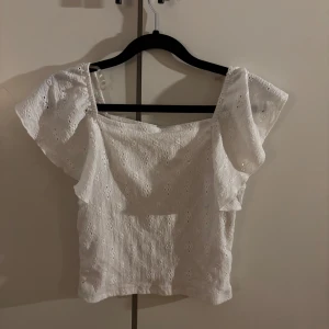 Vit blus med broderade detaljer Kappahl - Superfin vit blus från Kappahl med broderade hålmönster och volangiga ärmar. Lite nopprig.