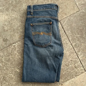 Helt nya nudie jeans - Säljer ett par klassiska blå jeans från Nudie som är modellen lean Dean. Jeansen är sprillans nya och har inte används någon gång och har fem fickor och den ikoniska Nudie-bågen på bakfickorna. Perfekta för dig som gillar en tidlös och clean look. 