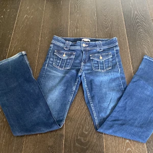 Blå jeans med fickdetaljer Gina Tricot - Snygga blå jeans från Gina Tricot med raka ben och fickor framtill med lock och knapp. passform. Jätte könt material!!!