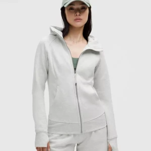 Ljusgrå zip hoodie från Lululemon - Säljer en ljusgrå hoodie från Lululemon med dragkedja framtill och huva. Tröjan har långa ärmar med tumhål och en slim passform som sitter snyggt. Perfekt för chill dagar eller till träning. Materialet är mjukt och skönt i bomullsblandning. Köpt för 1300