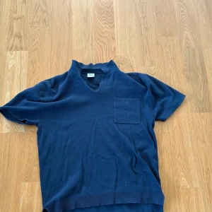 Mörkblå kortärmad tröja från Zara 164 - Snygg mörkblå tröja från Zara med korta ärmar och v-ringning. Tröjan har en bröstficka och ribbad nederkant. Perfekt för dig som gillar en clean och stilren look. Materialet känns mjukt och skönt mot huden. Strl 164cm. Köpt för 249kr mitt pris 119kr.