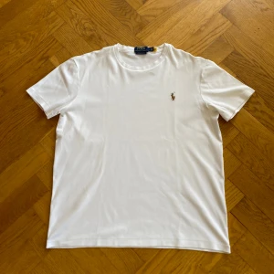 Vit slim t-shirt Ralph Lauren - Vit t-shirt från Polo Ralph Lauren med klassisk broderad logga på bröstet. Modellen är custom slim fit. Materialet är mjuk bomull som känns skönt mot huden. Skickar inom 2 dagar.