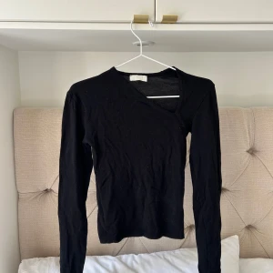 Svart v-ringad långärmad tröja från Le Ger by Lena Gercke - En svart långärmad tröja med v-ringning. Enkel och stilren modell som passar perfekt till jeans eller kjol. Tröjan har en smal passform och är gjord i ett mjukt material som känns skönt mot huden.