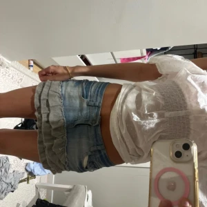 Jeanskjol med volangdetaljer - Supersöt kort jeanskjol med ljusblå tvätt och grå volangdetaljer längst ner. Kjolen är i en lågmidjad modell har klassiska fickor fram och bak. Perfekt för dig som vill ha en trendig och lekfull look i sommar.🩷 jättefint skick!🫶 W27