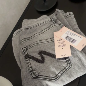 Grå bootcut jeans från Nelly - Snygga grå jeans från Nelly med bootcut passform och låg midja. Jeansen har markerade svarta sömmar och coola broderade detaljer på bakfickorna. Tillverkade i stretchig denim för en bekväm känsla och trendig look. Säljer då dom var fel storlek💕