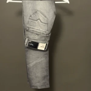 Grå jeans från Pepe Jeans Spike - Helt nya, Snygga grå jeans från Pepe Jeans, modell Spike, med regular fit och klassisk femficksdesign. Jeansen har en cool tvättad look, raka ben och tydliga sömmar på bakfickorna. Perfekta för dig som gillar stilrena och moderna jeans.