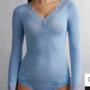 Ljusblå långärmad topp med spets - Supersöt ljusblå långärmad topp med v-ringning och fina spetsdetaljer vid halsringningen och ärmsluten. Sitter tight och är perfekt att styla med jeans eller kjol för en fräsch look. Strl: S köpte ny för 489kr så säljer inte för under 200kr!!🥰🙏🏼💗