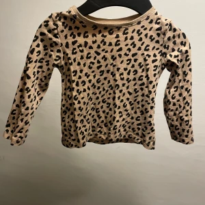 Leopardmönstrad långärmad tröja H&M - Säljer en beige långärmad tröja från H&M med svart leopardmönster. Tröjan är i mjuk bomull och har en klassisk passform med rund hals. Perfekt för dig som gillar djurmönster och vill ha en cool vardagsstil.