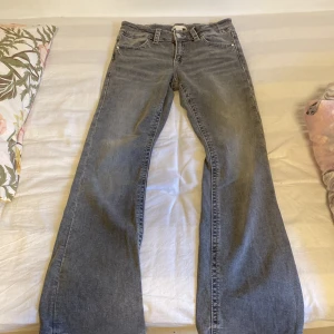 Gråa bootcut jeans från Gina Tricot - Snygga grå jeans från Gina Tricot i modell bootcut. Jeansen har klassisk femficksdesign, bälteshällor och är tillverkade i mjukt denimtyg. Perfekta för dig som gillar en avslappnad men trendig look.