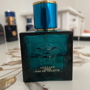 Versace Eros Edt  - Versace Eros Eau de Toilette i en stilren, fyrkantig flaska av turkost glas med Medusa-huvudet i relief på framsidan. Locket är metallicblått med gulddetaljer och Versaces ikoniska Medusa på toppen. En parfym som verkligen sticker ut. 30ml men ca halva återstår, mötas/frakt 
