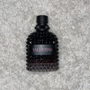 Valentino parfym  - Snygg parfym från Valentino i en mörk, nästan svart glasflaska med nitar och struktur. Flaskan har en lyxig känsla med rosa text på svart etikett och en robust svart kork. Perfekt för dig som gillar exklusiva dofter och cool design.