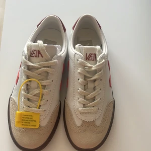 Vita Veja sneakers med röda detaljer - Jätte coola sneakers från veja. Lite förstora för mig och missade retur datumet så kan inte lämna tillbaka dem. Helt oanvända, endast testade! Original pris: 1600 kr