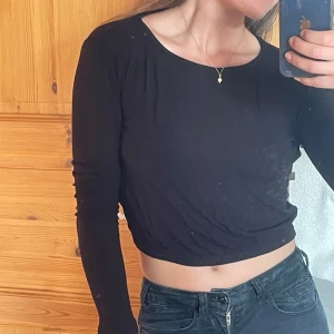 Svart croppad långärmad tröja - Svart croppad långärmad tröja från Gina Tricot i stretchigt och mjukt material. Enkel och stilren modell med rund halsringning, perfekt att matcha med höga jeans eller kjol. Snygg basic som funkar året runt.