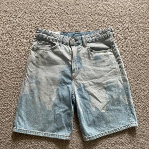Baggy shorts med blekt effekt - Tjaba! Säljer dessa riktigt snygga baggy shorts perfekta till sommaren. Shortsen har en liten fläck som knappt syns (se bild 2). Det står storlek 32 men de passar mig som har M/L i byxor. Tveka inte o DM:a frågor eller prisförslag. ✌️