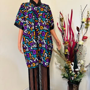 Färgglad mönstrad klänning med fransar - Unik klänning med färgstarkt grafiskt mönster i lila, orange, turkos, svart och vitt. Oversized passform, kort ärm och svart krage. Lång fransdetalj nedtill som ger extra edge. Perfekt för dig som vill sticka ut med din stil. Följ oss på Instagram; @shop_with_tyra