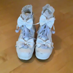 Vita Lolita Skor i Klack💕🎀 - Supersöta med chunky klack, dekorerade med stora rosetter och volanger😻☺️ Skorna har snörning framtill, dragkedja på sidan och platt sula framtill!🎀 PERFEKT för dig som gillar kawaii eller lolita-stil🌸 Använt några gånger, därför lite smutsiga, men endast det som visas i bilderna🤗 🚚 Skickar inom kort!