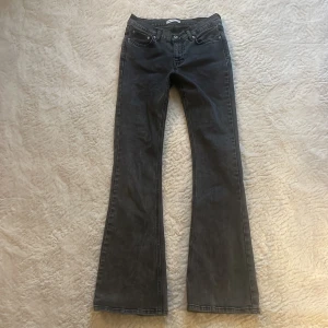 Svarta bootcut jeans - Snygga svarta bootcut jeans med låg midja och klassisk femficksdesign. Jeansen har en lätt utsvängd passform nertill och är tillverkade i ett mjukt denimtyg som sitter skönt på kroppen. Perfekta för dig som gillar en retro vibe och vill ha ett par jeans som sticker ut.