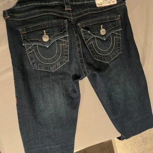 True Religion jeans Joey - Bootcut lågmidjade True Religion jeans i storlek 26w. Inga defekter. Avklippta dock en liten bit. Innerbena på 72cm och midjemått på 37cm. Säljer för dom är lite för korta för mig. Pris kan alltid diskuteras. 💕 ordinarie pris 1600kr