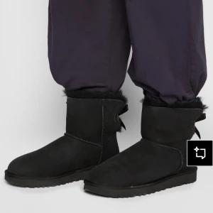 Svarta UGG boots med rosett - Mysiga svarta boots från UGG i mocka med fluffigt foder och söt rosettdetalj bak. Skorna har rund tå, platt sula och är perfekta för kalla dagar. Klassisk UGG-look med extra twist tack vare rosetten. De är köpta förra vintern har kvar kvitto låda och alla tillbehör kan skicka privata bilder 