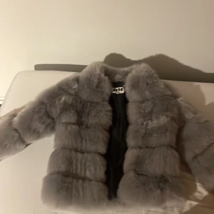 Grå pälsjacka från Dennis Maglic - Säljer en fluffig och lyxig grå pälsjacka från Dennis Maglic i storlek S.Jackan är använd 2 gånger. Jackan har lång ärm, bred krage och är tillverkad i mjukt pälsmaterial. Perfekt för dig som vill sticka ut och hålla dig varm med stil.