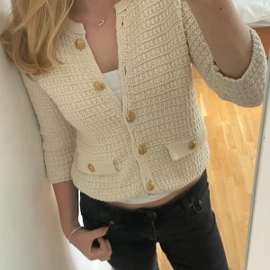 Beige stickad kofta - Superfin beige stickad cardigan jacka med guldiga knappar och två små fickor framtill samt trekvarts ärmar. Jättefin och trendig. Köparen står för frakt 